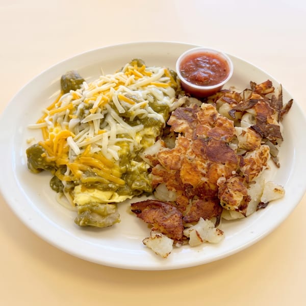 Scrambled eggs with green chile and cheese, crispy hash browns, and salsa.