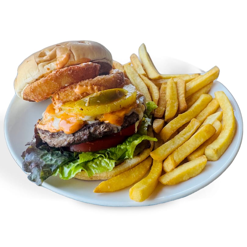 A cheeseburger with lettuce, tomato, pickles, and onion rings, served with a side of french fries.