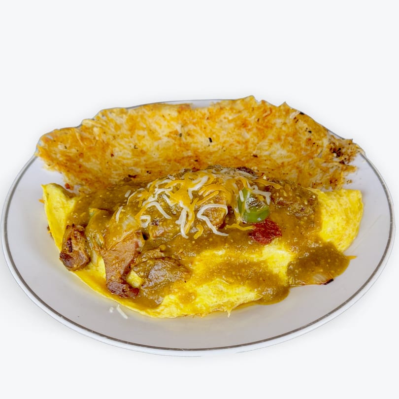 A plate of omelet covered in green chili sauce, cheese, and meat, with hash browns.